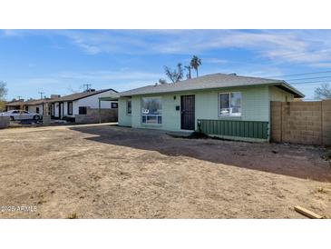 Ranch style home with a large front yard and a green brick facade at 3821 W Verde Ln, Phoenix, AZ 85019