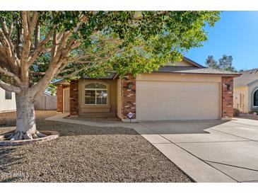 Charming single-story home with a two-car garage, brick accents and mature tree at 8549 E Carol Ave, Mesa, AZ 85208