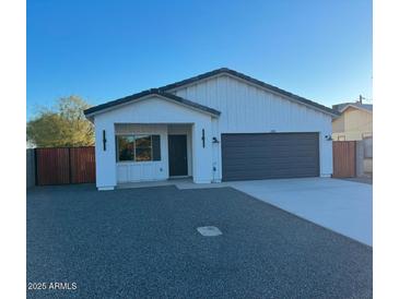 New construction home with modern exterior, two-car garage, and wood gate at 205 E Jackson Ave, Buckeye, AZ 85326