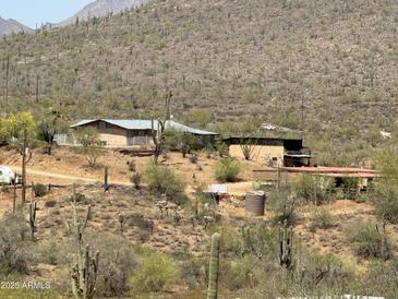 Rustic desert home features a metal roof, multiple buildings, and natural surroundings at 42213 N 3Rd St, Phoenix, AZ 85086