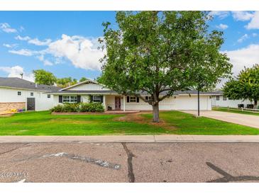 Charming home featuring a large tree, green lawn, and a classic white facade at 4525 E Calle Ventura --, Phoenix, AZ 85018