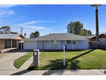 Charming single-story home with a well-manicured lawn, blue exterior and a driveway leading to an attached garage at 914 N Cameron Ave, Casa Grande, AZ 85122