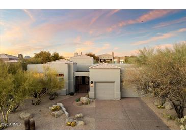 Desert landscape surrounds this single-story home with a neutral facade and two-car garage at 11060 E Mark Ln, Scottsdale, AZ 85262