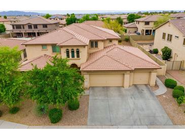 Two-story house with three car garage, landscaped yard, and mountain views at 15296 W Coolidge St, Goodyear, AZ 85395