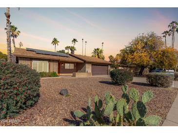 Single-story home with desert landscaping, a two-car garage, and solar panels at 4944 E Windrose Dr, Scottsdale, AZ 85254