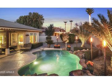 Inviting backyard pool with lush landscaping, tiki torches, and ambient lighting perfect for outdoor entertaining at 953 E Fieldstone Pl, Chandler, AZ 85249