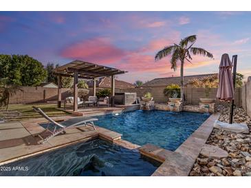 Stunning backyard with a pool, spa, pergola, and comfortable seating area at 14309 W Cypress St, Goodyear, AZ 85395