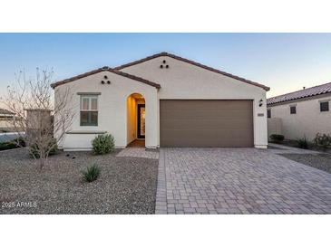 Single-story home with brown garage door and landscaped front yard at 18055 W Muirwood Dr, Goodyear, AZ 85338