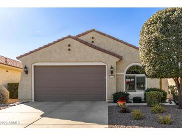 Tan one-story house with brown garage door and landscaping at 26541 W Ross Ave, Buckeye, AZ 85396