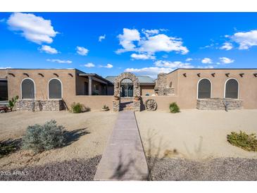 Spanish-style home with stone arch entry and landscaped walkway at 37209 N 12Th St, Phoenix, AZ 85086