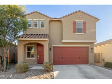 Two-story house with red garage door and landscaping at 40561 W Hillman Dr, Maricopa, AZ 85138