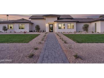 Inviting single-story home featuring a stone facade, manicured landscaping, and a walkway leading to the front door at 6614 E North Ln, Paradise Valley, AZ 85253