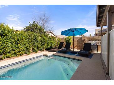 Inviting backyard oasis featuring a sparkling pool, lounge chairs, and a patio umbrella at 1328 E Binner Dr, Chandler, AZ 85225