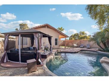 Inviting backyard with a sparkling pool, gazebo, and comfortable seating at 1616 N 125Th Ln, Avondale, AZ 85392