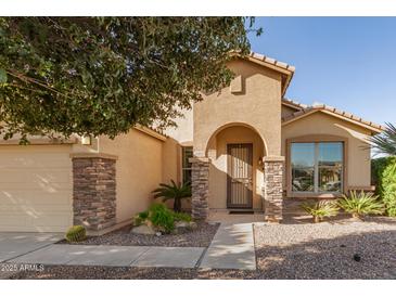 Tan house with stone accents, arched entryway, and landscaped yard at 31032 N Obsidian Dr, San Tan Valley, AZ 85143