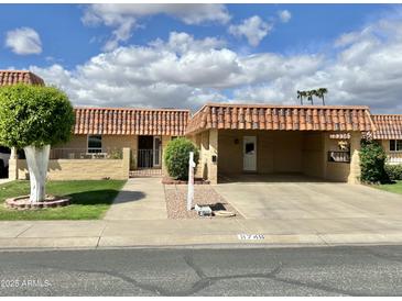 Charming single-story home with a carport and well-maintained desert landscaping under a partly cloudy sky at 9746 N 105Th Dr, Sun City, AZ 85351