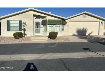 Tan single-story home with attached garage, green awning, and landscaping at 3301 S Goldfield Rd # 4086, Apache Junction, AZ 85119