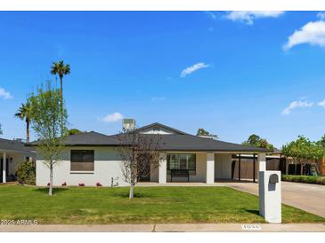 Charming single-story home featuring a manicured lawn, carport, and inviting front porch with a bench at 1036 E Glenn Dr, Phoenix, AZ 85020