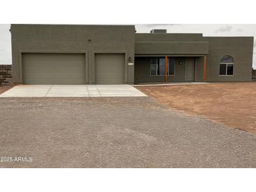 Single story home with three-car garage and desert landscaping at 29340 N 231St Ave, Wittmann, AZ 85361