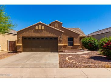 Single-story house with brown exterior, two-car garage, and landscaped front yard at 36532 W Barcelona Ln, Maricopa, AZ 85138