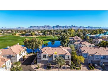 Stunning aerial view of a townhouse overlooking a lush green golf course and sparkling lake with mountain views at 8989 N Gainey Center Dr # 222, Scottsdale, AZ 85258
