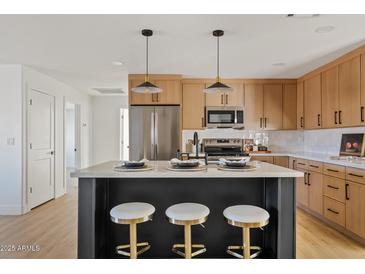 Modern kitchen with island, stainless steel appliances, and light wood cabinets at 4129 E Eugie Ave, Phoenix, AZ 85032