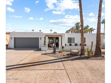 White mid-century modern home with gray garage door and landscaped front yard at 4437 N Granite Reef Rd, Scottsdale, AZ 85251