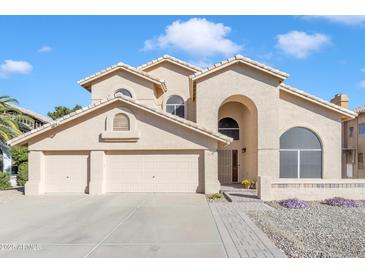 Inviting Southwestern home with an arched entryway, three-car garage, and well-maintained landscaping at 4968 E Grandview Rd, Scottsdale, AZ 85254