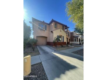 Two-story house with tan and red exterior, two-car garage, and landscaping at 7827 W Cypress St, Phoenix, AZ 85035