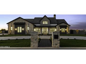 Stunning stone and stucco home with modern black trim and manicured lawn, captured at twilight at 19912 E Karsten Dr, Queen Creek, AZ 85142