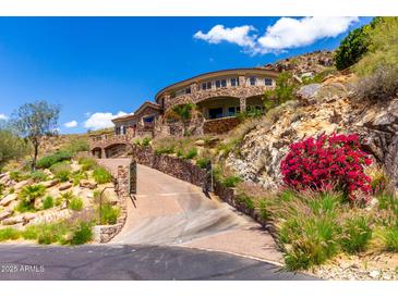 Stunning stone mansion perched on a hillside with a private drive, lush landscaping, and scenic views at 7929 N 55Th St, Paradise Valley, AZ 85253