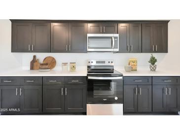Modern kitchen with dark cabinetry, stainless steel appliances, and ample counter space at 1344 W Inca Dr, Coolidge, AZ 85128