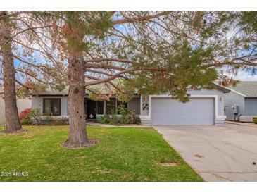 House exterior features a gray color scheme, a two-car garage, and a well-maintained lawn at 1427 E Irwin Ave, Phoenix, AZ 85042