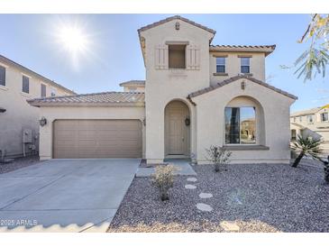 Two-story house with tan exterior, brown door, and stone landscaping at 15461 W Jenan Dr, Surprise, AZ 85379