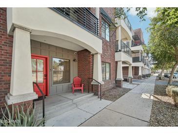 Inviting condo front porch with brick accents, red door and comfortable outdoor seating at 475 N 9Th St # 115, Phoenix, AZ 85006