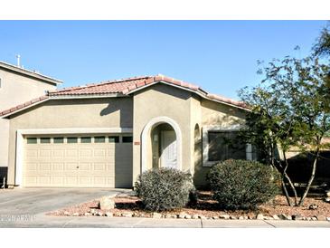Tan house with a two-car garage and landscaping at 13915 N 132Nd Ln, Surprise, AZ 85379