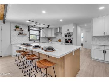 Modern kitchen with white cabinets, quartz countertops, and stainless steel appliances at 6613 W Sweetwater Ave, Glendale, AZ 85304