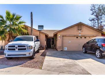 Tan house with a two-car garage and a landscaped yard at 8717 W Wilshire Dr, Phoenix, AZ 85037
