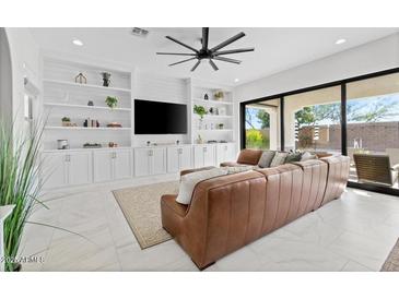 Spacious living room with built-in shelving and sliding glass doors leading to backyard at 10713 E Hawk Ave, Mesa, AZ 85212