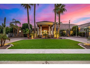 Grand estate with a circular driveway, lush landscaping, and a captivating sunset backdrop at 3731 E Halifax Cir, Mesa, AZ 85205