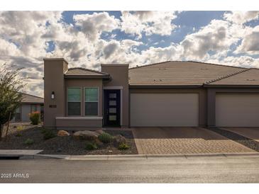 Modern two-car garage home with stone landscaping and neutral exterior at 17609 E Bismark Lake Ct, Rio Verde, AZ 85263