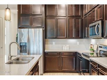 Modern kitchen with dark cabinetry, stainless steel appliances, and a kitchen island at 6565 E Thomas Rd # 1005, Scottsdale, AZ 85251