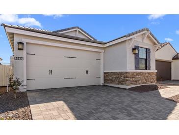 View of the home's garage with attractive stone accents and a paved driveway at 4419 N 203Rd Ave, Buckeye, AZ 85396