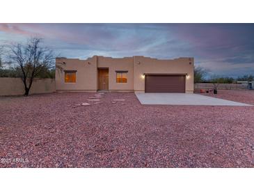 Tan stucco house with brown garage door, stone pathway, and gravel yard at 38913 N 21St Ave, Phoenix, AZ 85086
