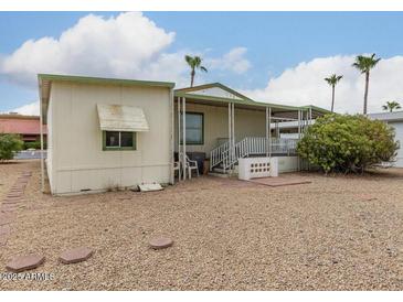 Tan mobile home with green awning, covered patio, and desert landscaping at 11596 W Sierra Dawn Blvd # 357, Surprise, AZ 85378