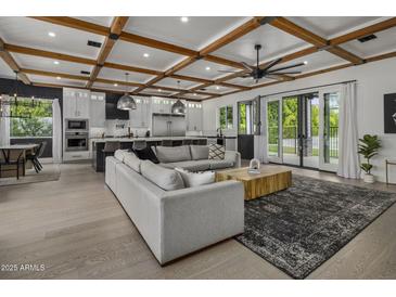 Open-concept living room with a decorative ceiling, large sofa, and seamless flow into the modern kitchen at 3322 N Valencia Ln, Phoenix, AZ 85018