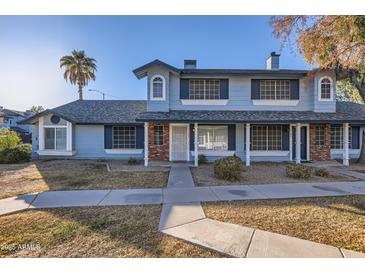 Two-story townhome with brick and blue siding, featuring a walkway and landscaping at 10101 N 91St Ave # 81, Peoria, AZ 85345