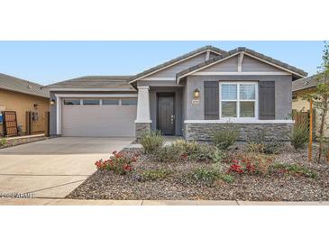 Single-story home with gray siding, stone accents, and landscaping at 36530 W Leonessa Ave, Maricopa, AZ 85138