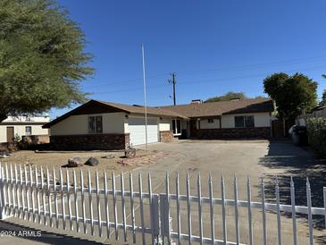 Ranch style home with brick facade, white picket fence, and a spacious driveway at 6131 N 36Th Dr, Phoenix, AZ 85019