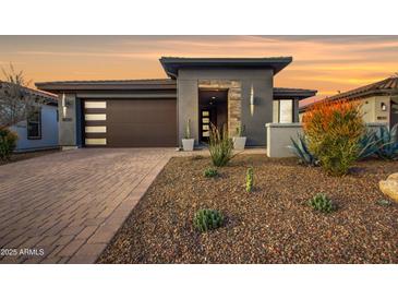 Modern home with a brown sectional garage door, desert landscaping, and stone accents at sunset at 17527 E Silver Sage Ln, Rio Verde, AZ 85263